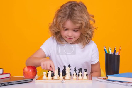 Téléchargez les photos : Child with chess on yellow isolated studio background. Clever concentrated and thinking child playing chess. Child boy developing chess strategy, playing board game - en image libre de droit