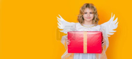 Téléchargez les photos : Cute blonde kid angel with gift box present. Child at angel costume. Banner for website header design - en image libre de droit