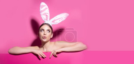 Téléchargez les photos : Horizontal photo banner for website header design. Easter funny woman with rabbit ears. Portrait of a pretty lovely girl isolated on pink banner, copy space. Blank poster banner - en image libre de droit