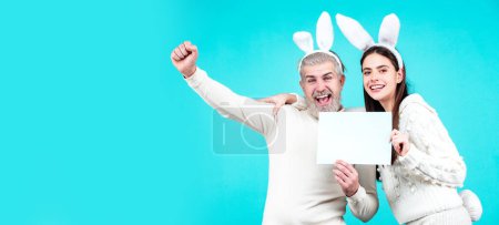 Téléchargez les photos : Excited Easter couple in bunny ears and rabbit costume on blue background isolated. Wide photo banner for website header design - en image libre de droit
