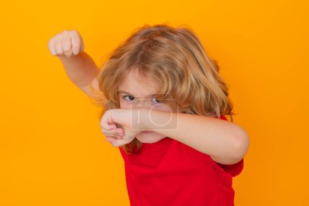 Photo for Andry boy in red t-shirt making stop gesture on isolated studio background. Kid showing warning symbol, hand sign no. Child with fist gesture fight - Royalty Free Image