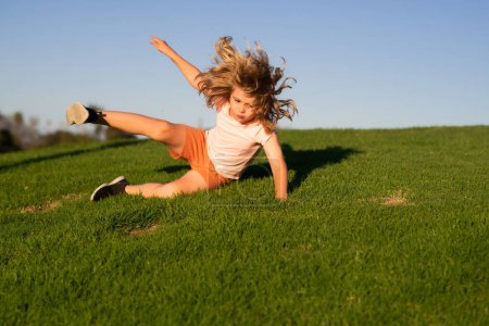 Foto de Kid runs through the spring grass and falling down on the ground in park. Moment of the fall down. Little child tripped and falls down. Fall risk for children. The moment of the fall. Clumsy kid - Imagen libre de derechos
