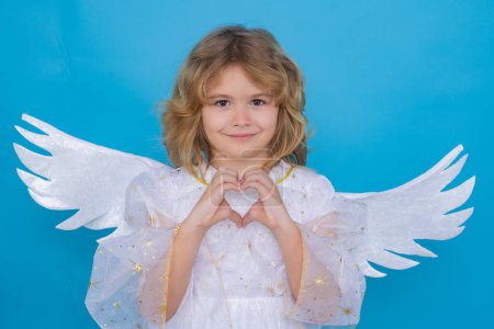 Foto de Little cute child at angel costume on isolated background. Kid with angel wings. Isolated studio shot. Funny angel - Imagen libre de derechos