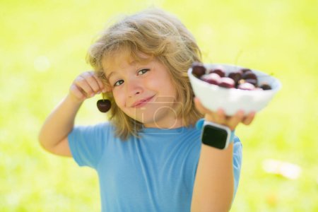 Photo for Summer child face. Cute little boy eating cherries, making funny faces and playing with the cherries, having fun - Royalty Free Image