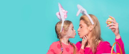 Foto de Easter banner, mockup copy space, poster flyer header for website template. A mother and her daughter painting Easter eggs and kissing. Happy family preparing for Easter - Imagen libre de derechos