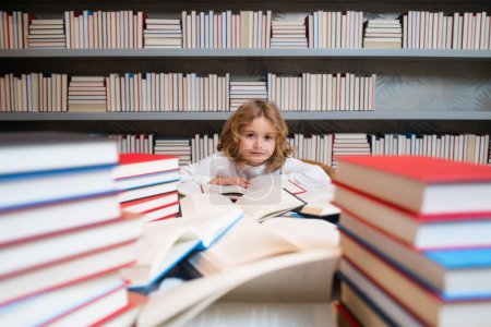 Téléchargez les photos : Child reading book in a book store or school library - en image libre de droit