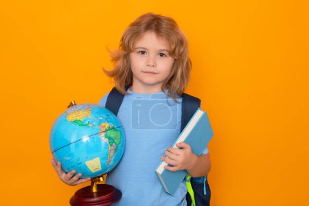 Foto de Back to school. School kid hold world globe and book. Back to school. Funny little student boy from elementary school with book. Pupil on studio isolated background - Imagen libre de derechos