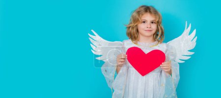 Téléchargez les photos : Angel kid with heart. Child at angel costume. Kid with angel wings. Isolated studio shot. Banner header with copy space - en image libre de droit