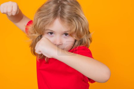 Photo for Child with fist gesture fight. Andry child boy in red t-shirt making stop gesture on isolated studio background. Kids protection, bullying, abuse and violence concept - Royalty Free Image