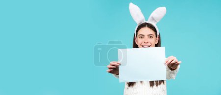 Téléchargez les photos : Easter bunny girl hold paper for text. Easter bunny rabbit - copy space, text concept. Empty paper. Panoramic web banner frame - en image libre de droit