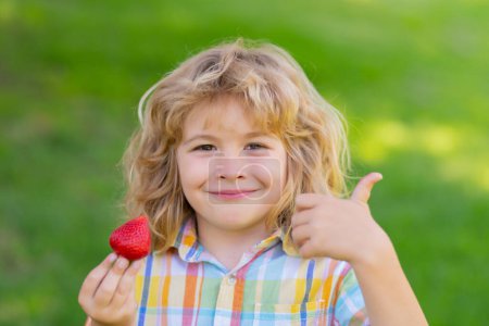 Foto de Kid picking and eating ripe strawberry. Happy child holding fresh fruits berry strawberry. Healthy organic berry strawberries fruit, summer season - Imagen libre de derechos