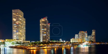 Téléchargez les photos : View of Miami at sunset, USA. Miami city skyline panorama at dusk with urban skyscrapers and bridge over sea with reflection - en image libre de droit