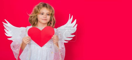 Téléchargez les photos : Angel kid with heart. Valentine angel. Little cupid child. Kid angel with angels wings, isolated on red studio background. Valentines day gift card. Horizontal header, banner - en image libre de droit