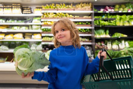 Téléchargez les photos : Child with cabbage. Child choosing fruits and vegetables during shopping at vegetable supermarket - en image libre de droit