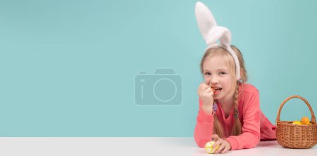 Téléchargez les photos : Easter child. Funny girl wearing bunny ears and having fun with Easter eggs. Cute little child girl wearing bunny ears on Easter day. Panoramic web banner frame - en image libre de droit