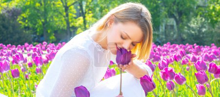 Foto de Spring woman with tulips banner. Beauty spring woman with tulip Flovers. Young woman relaxing in the tulips fields - Imagen libre de derechos