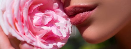 Foto de Lips and rose, close up spring banner. Beautiful female mouth. Plump full lips. Beautiful woman lips with rose - Imagen libre de derechos