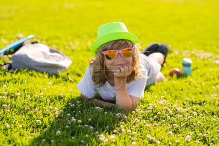 Foto de Kid boy girl resting on green grass. Happy child enjoying on grass field and dreaming. Summer holiday - Imagen libre de derechos