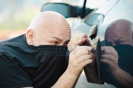 Téléchargez les photos : Close up car thief stealing car. Unlocked car, man trying to break into inside - en image libre de droit