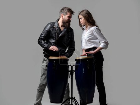 Téléchargez les photos : Couple hitting on conga drums isolated on gray background. Man and woman playing conga drums - en image libre de droit