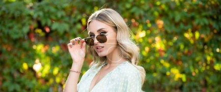 Foto de Portrait of sensual woman in spring background. Banner for website header. Portrait of beautiful young woman in sunglasses. Outdoor portrait of a cute girl. Happy cheerful female model, close up face - Imagen libre de derechos