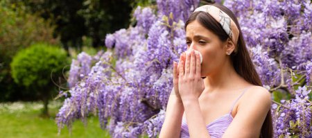 Photo for Spring allergy, flu. Banner. Girl with nose allergy sneezing. Polen illnes symptom concept. Woman allergic to blossom during spring blooming tree outdoor - Royalty Free Image