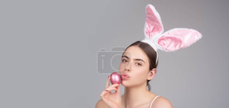 Foto de Bunny girl with easter egg. Rabbit girl with color egg. Woman in rabbit ears. Wide photo banner for website header design - Imagen libre de derechos