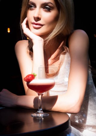 Foto de Young girl drinking a cocktail. Summer refreshment. Woman face, fashion stylish female portrait. Beautiful woman drink cocktail in bar at night - Imagen libre de derechos