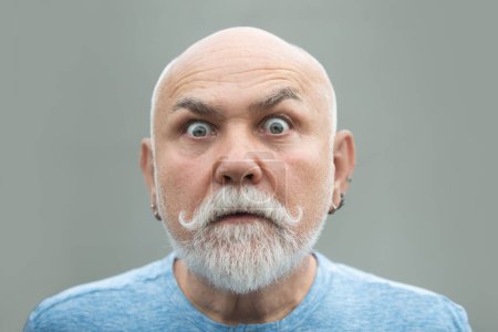 Foto de Surprised old mature man face. Closeup emotional portrait of an old mature senior man with grey beard isolated on studio background. Emotions faces - Imagen libre de derechos