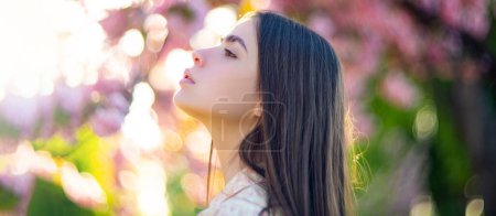 Foto de Sensual woman near sakura tree background, banner for website header. Beautiful young woman posing outdoor. Stylish girl in summer casual outfit. Outdoor female portrait - Imagen libre de derechos