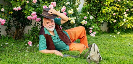 Téléchargez les photos : Homme aîné à Rose Garden. Jardiniers aux fleurs printanières. Grand-père travaillant dans le jardin - en image libre de droit