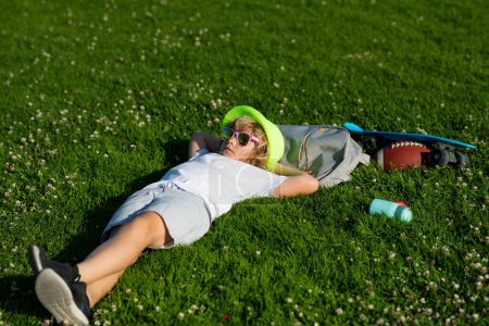 Téléchargez les photos : Child relax at the summer park. Kid boy lying on green grass outdoor. Carefree kid boy having fun on spring day at the park - en image libre de droit