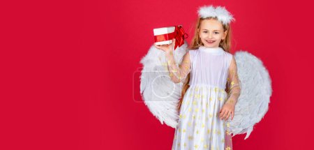 Téléchargez les photos : Angel child banner, isolated studio background. Angel children girl with white wings Cute baby child with angel wings. Angel kids with present gift, studio portrait - en image libre de droit