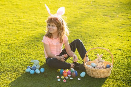 Photo for Easter bunny kids. Child boy in bunny Easter ears painting eggs. Cute little boy, easter bunny children spring outdoor - Royalty Free Image
