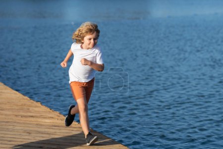 Téléchargez les photos : Little runners outdoors in summer nature. Sporty child running in a park. Outdoor sports and fitness for children. Happy childhood - en image libre de droit