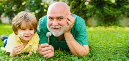 Foto de Grandfather and grandson on sky background, spring banner. Happy family father and child on meadow with a kite in the summer on green grass - Imagen libre de derechos