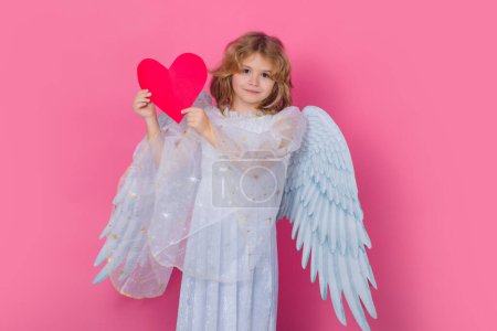 Téléchargez les photos : Little angel with heart symbol love and valentines day. Valentine angel. Little cupid child. Kid angel with angels wings, isolated on pink studio background. Valentines day gift card - en image libre de droit