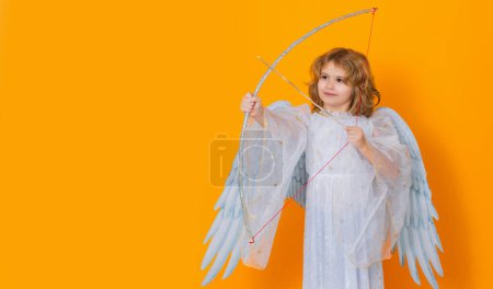 Téléchargez les photos : Banner. Angel with bow and arrow. Valentine angel. Little cupid child. Kid angel with angels wings, isolated on yellow studio background. Valentines day gift card - en image libre de droit