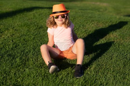 Foto de Kid boy girl resting on green grass. Kid boy relax at park outdoor. Summer weekend. Summertime vacation - Imagen libre de derechos