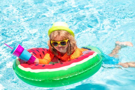 Foto de Child in swimming pool playing in water. Vacation and traveling with kids. Children play outdoors in summer. Kid with floating ring. Summer swimming and relax, swim on ring in pool, poolside - Imagen libre de derechos
