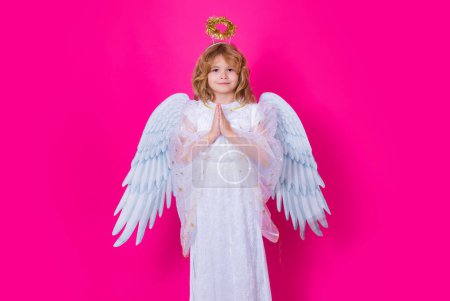 Téléchargez les photos : Angel prayer. Child at angel costume with prayer hands, hope and pray concept. Kid with angel wings. Isolated studio shot - en image libre de droit