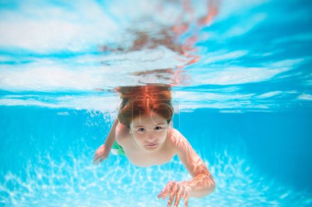 Téléchargez les photos : Child swimming underwater in swimming pool. Funny kids boy play and swim in the sea water. Kids swim on summer vacation - en image libre de droit