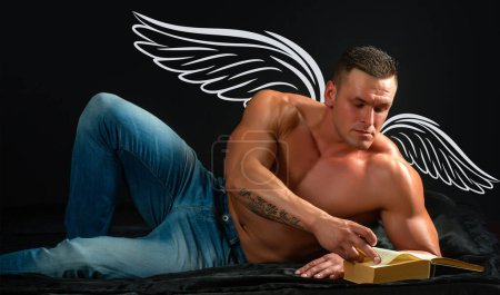 Foto de Photo banner of sexy man angel with wings for valentines day. Sexy naked attractive man with naked body in bed reading a book. Night gay concept. Wellness, wellbeing concept - Imagen libre de derechos