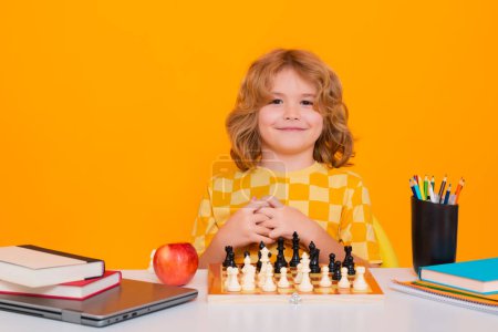 Téléchargez les photos : Child play chess on studio background. Clever concentrated and thinking child playing chess. Child boy developing chess strategy, playing board game - en image libre de droit