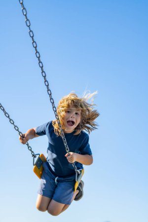 Photo for Childhood. Funny kid on swing. Little boy swinging on playground. Happy cute excited child on swing. Cute child swinging on a swing. Crazy playful child swinging very high on sky - Royalty Free Image