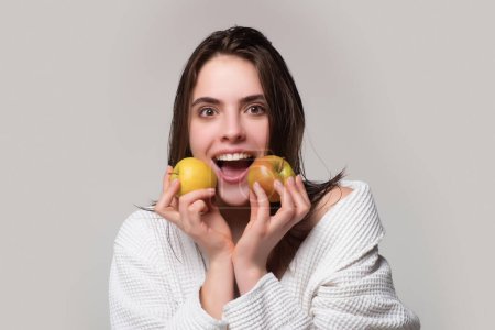 Téléchargez les photos : Woman with apples. Healthy teeth. Beautiful woman with white teeth holding apple and smiling. Posing on gray studio background. Healthcare and dental care concept - en image libre de droit
