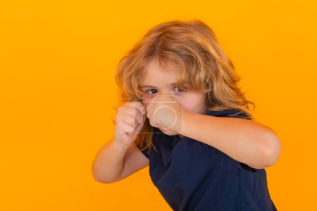 Photo for Angry child with fist gesture fight, hit on studio isolated background. Boy fight, battle. Kid boy with mad expression handed punch. Bad kids behavior. Fury boy - Royalty Free Image