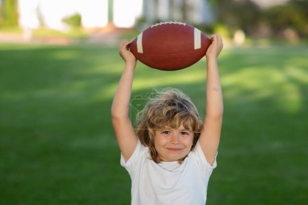 Téléchargez les photos : Football game, rugby, american football. Child boy playing football outdoor - en image libre de droit