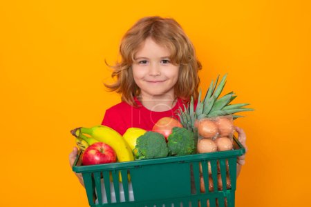 Photo for Child with hopping basket, isolated on yellow background. Shopping grocery. Child with shopping basket and grocery. Kids buying groceries in supermarket. Boy in shop - Royalty Free Image