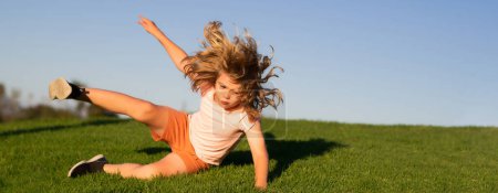 Photo for Kid runs through the spring grass and falling down. Moment of the fall down. Little child tripped and falls down. The moment of the fall. Spring and kid. Wide photo banner for website header - Royalty Free Image